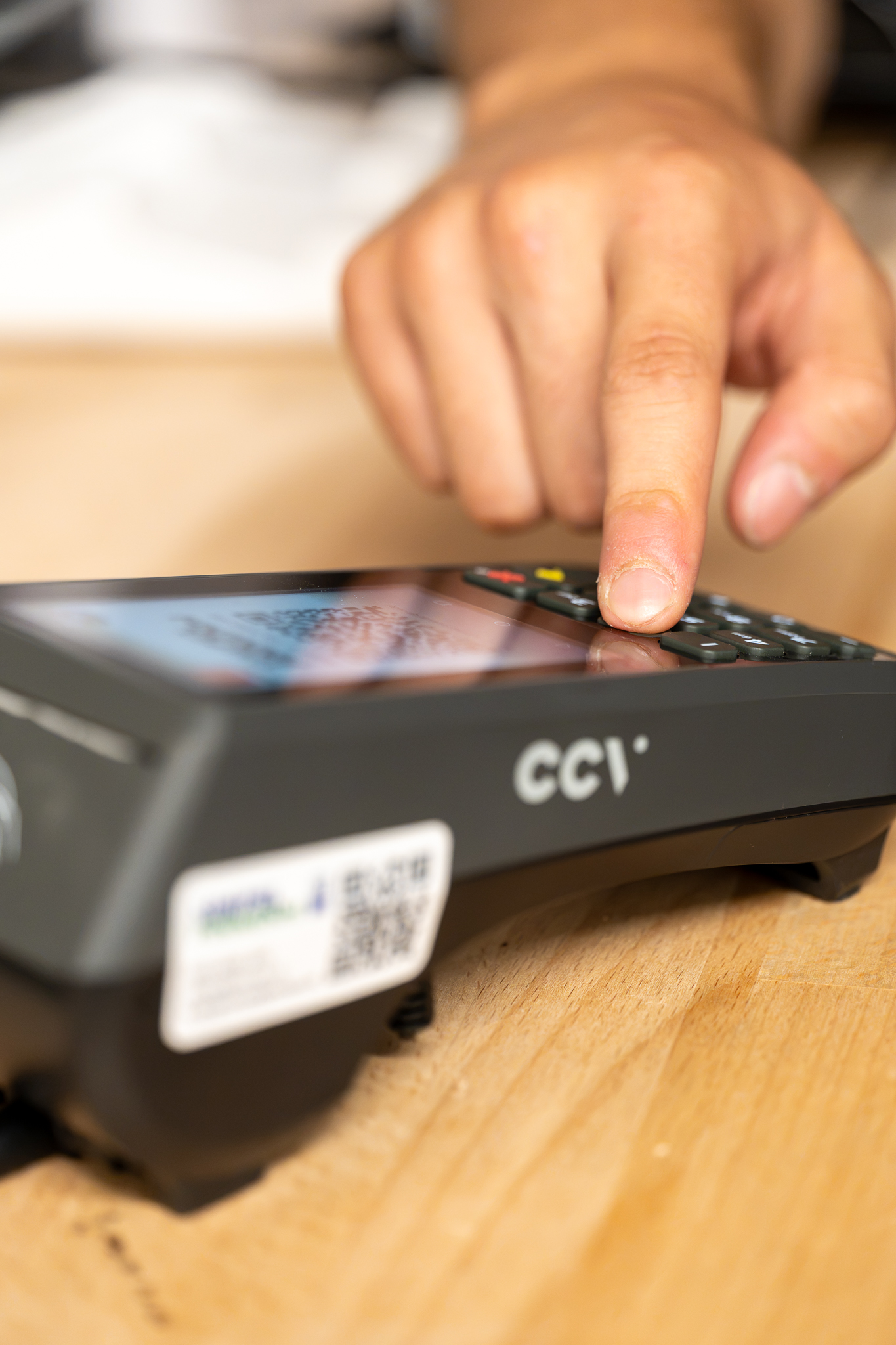 Hand tapping a card payment terminal on a counter