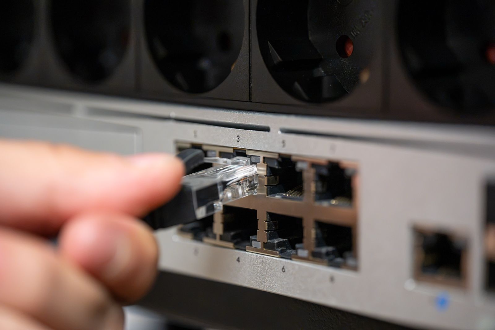 Engineer connecting a network cable to a managed switch